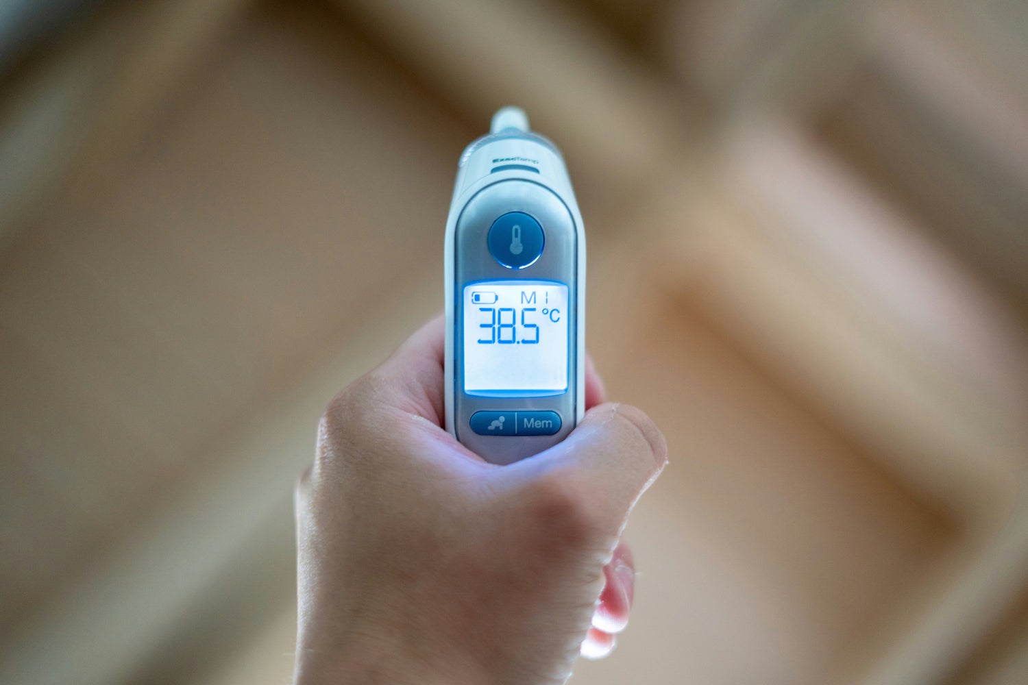 Handheld digital baby thermometer showing a temperature reading on a backlit screen